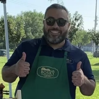 Joel Lee Ozuna smiling outdoors in a Bosky Strings apron