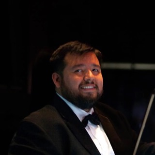 Miguel Javier Gutierrez in a tuxedo performing with his violin on stage